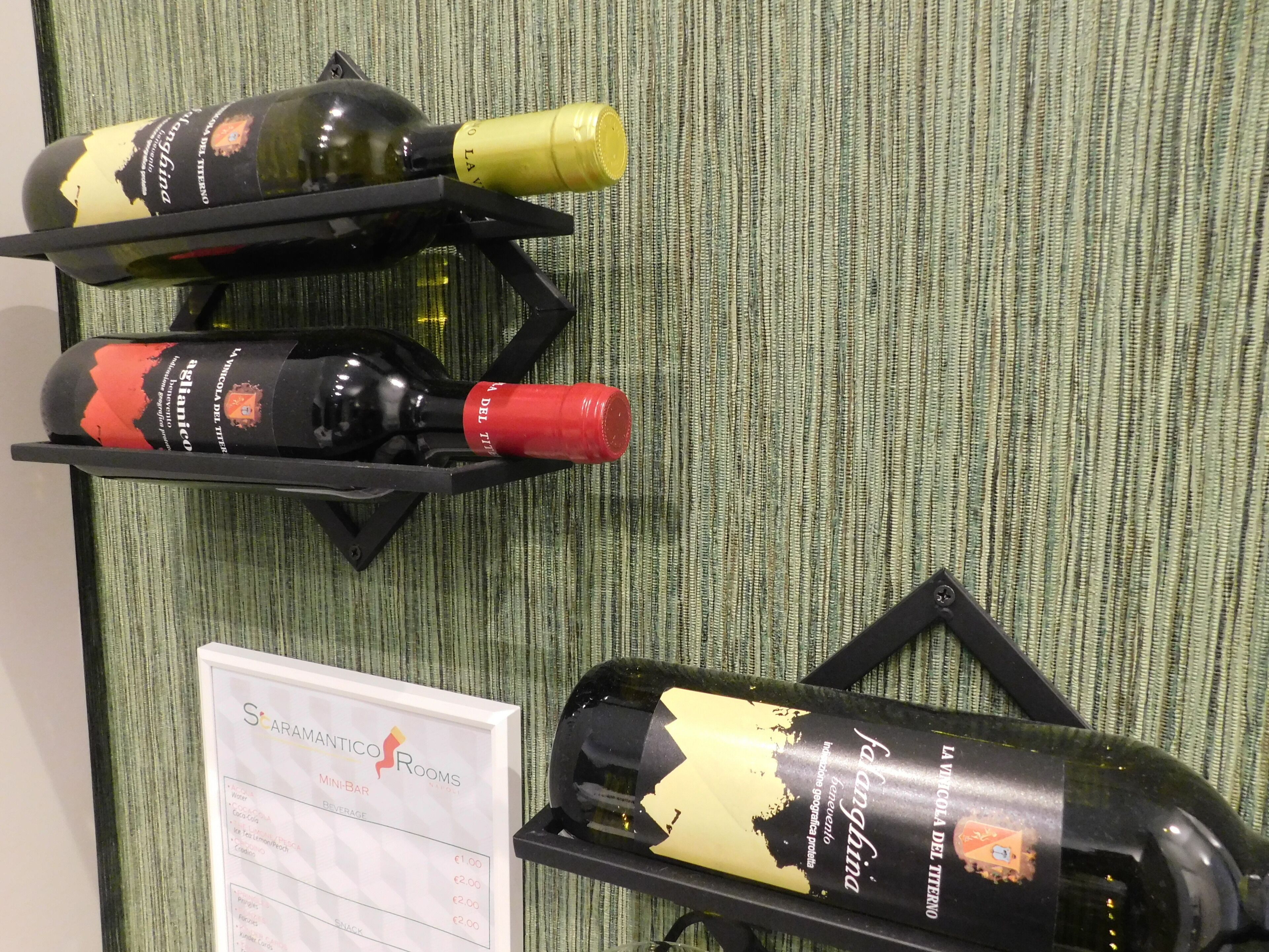 Tres botellas de vino sobre pedestales negros frente a un fondo verde texturizado.