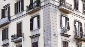 A building with multiple balconies, a street sign, and a tourist bus advertisement.