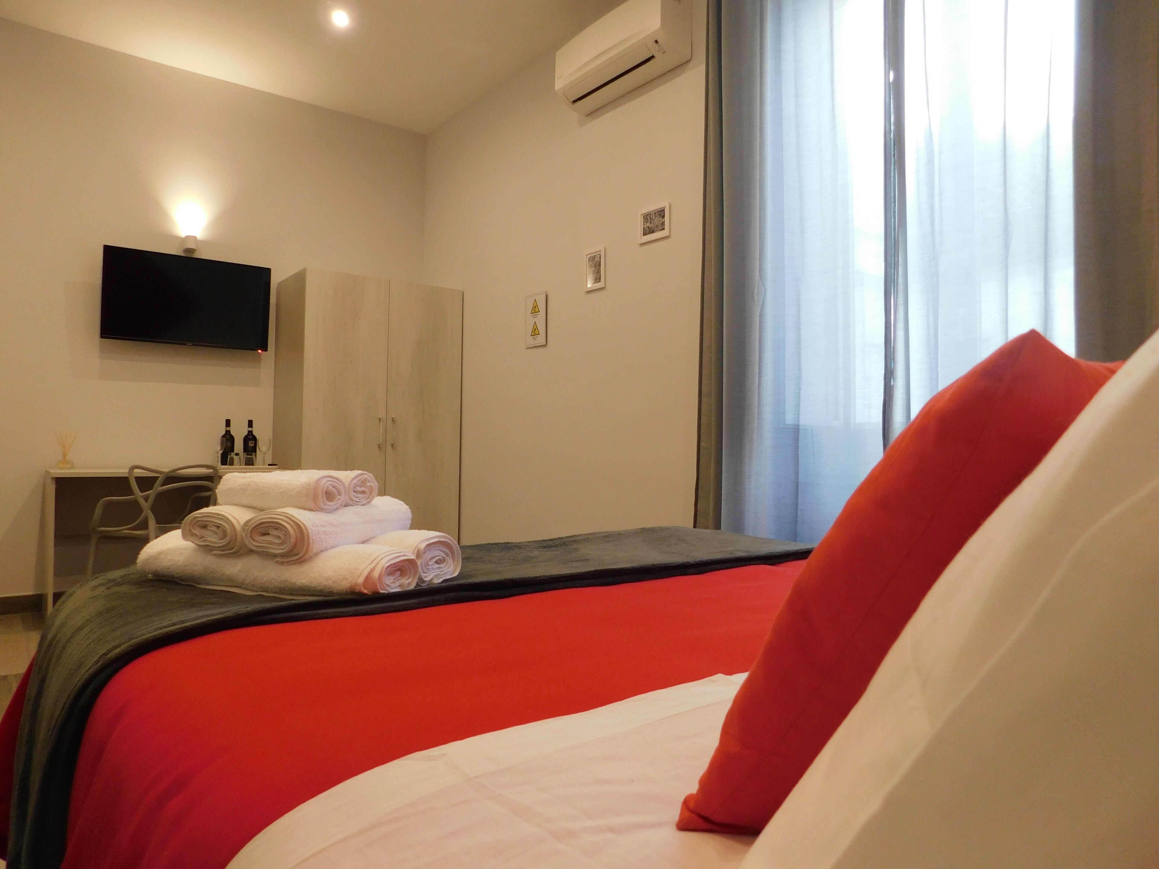 A hotel room with a bed, a desk, a chair, and a television on the wall.