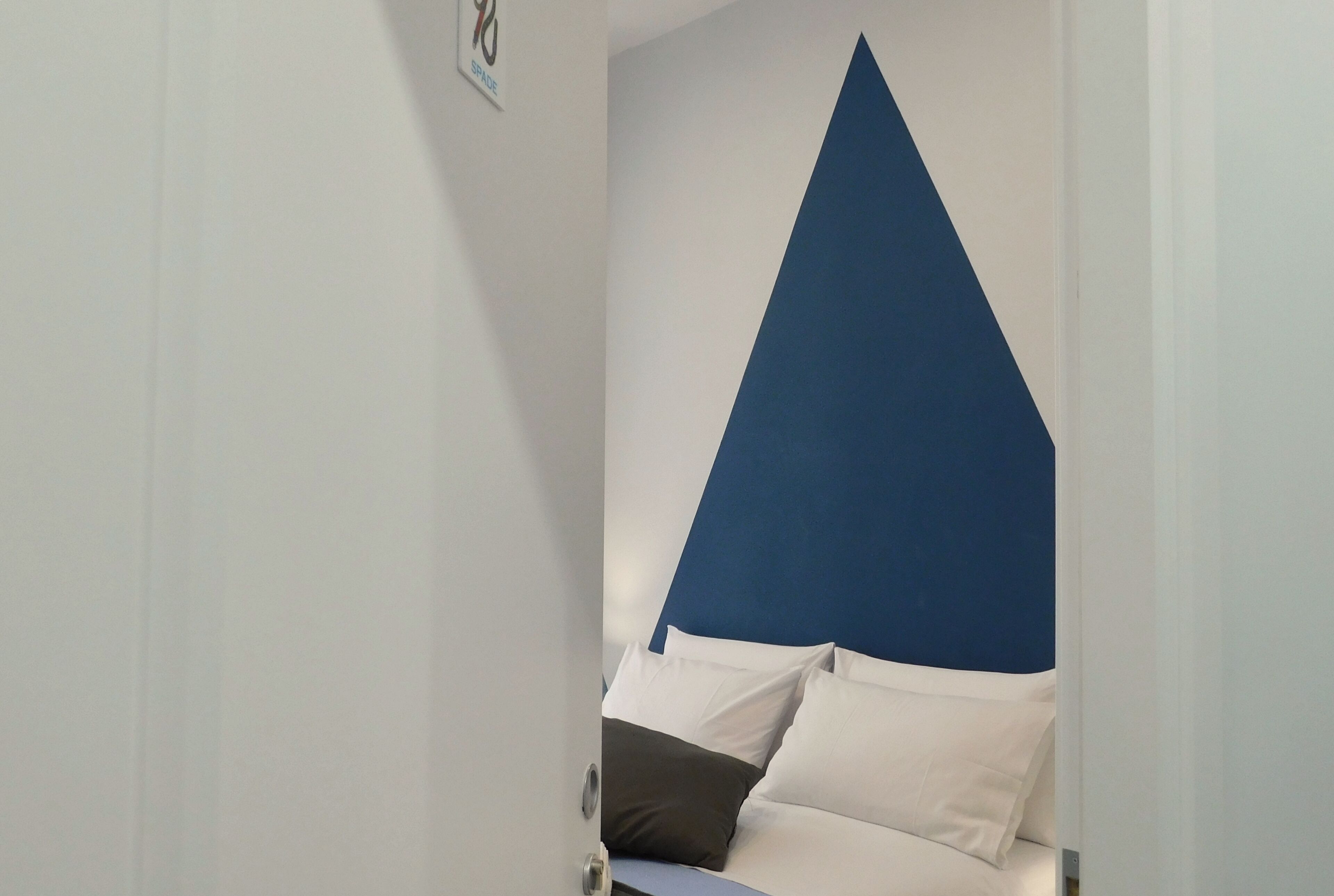 A room with a bed, white walls, and a blue accent wall.