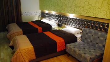 Habitación de hotel con dos camas, una mesita de noche, una lámpara y un cabecero estampado.