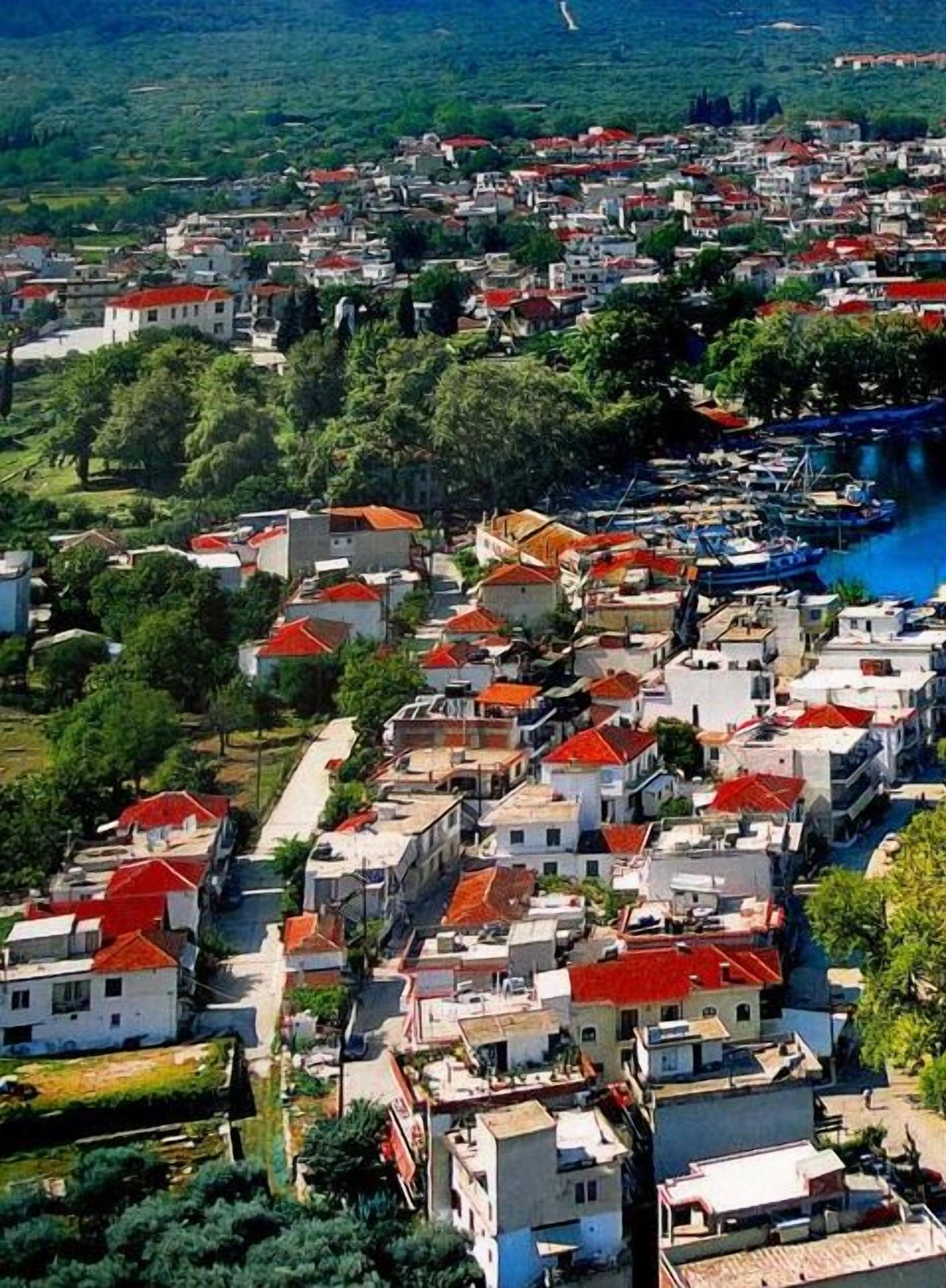 Una vivace cittadina costiera con case addossate, un porto turistico e un fiume.