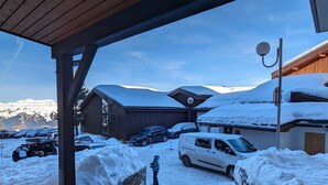 Un espacio exterior nevado con un corredor cubierto que lleva a un edificio de techo inclinado.