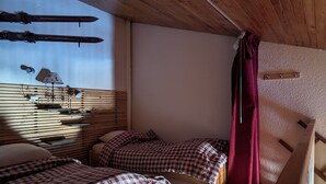 Una cabaña de madera con dos camas, techo de madera y ventana con vistas.