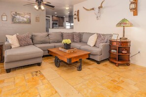 A living room with a gray sectional sofa, a wooden coffee table, and a decorative lamp.