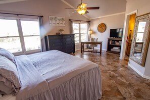 Un dormitorio con cama, escritorio, silla, televisor y un espejo grande.