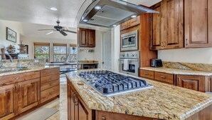 A kitchen with wooden cabinets, a granite countertop, a gas range, and a built-in oven. - Private Hilltop Farmhouse Incredible Views, Petting Zoo Animals & Hot Tub (Fredericksburg)