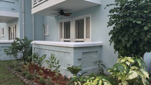 A building with a balcony, a ceiling fan, and a window with shutters. - The Point, Negril -1 BR, Ocean & beaches, Pool, Tennis, Snorkel 5 star location! (Negril)