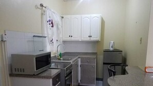 A compact kitchen with a microwave, sink, and small refrigerator. - Unity Villa (Montego Bay)