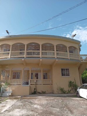 A two-story building with a balcony on the upper floor, featuring decorative railings and barred windows.
