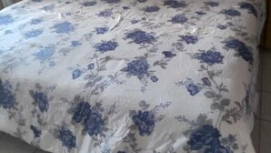 A bed with a floral bedspread and a wooden headboard. - Unity Villa (Montego Bay)
