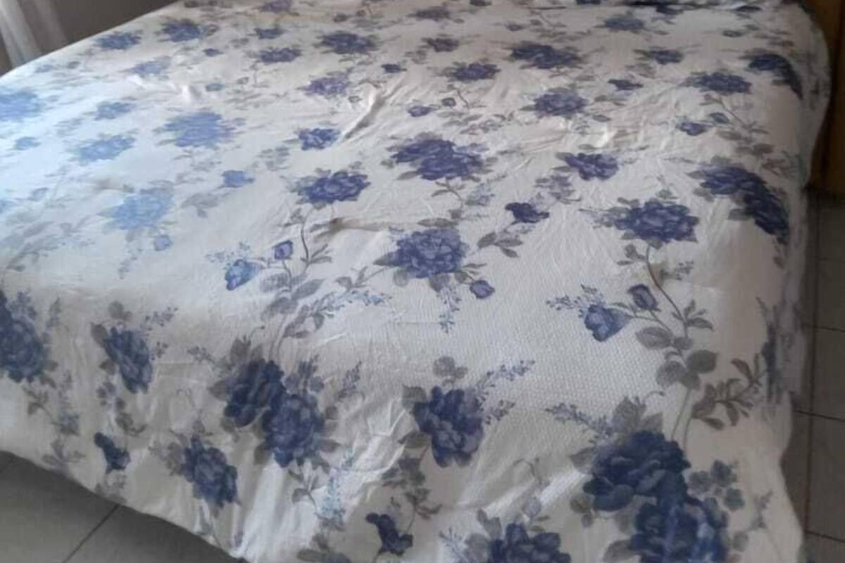 En säng med ett blommigt överkast och en sänggavel i trä.