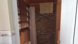 A small bathroom with a toilet, sink, and shower. - Unity Villa (Montego Bay)