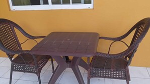 A table and two wicker chairs against a yellow wall, with a window above. - Unity Villa (Montego Bay)