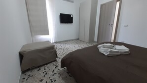 Et hotelværelse med seng, et lille bord, et fjernsyn og et klædeskab.