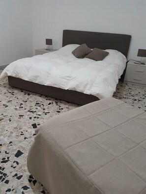 A bedroom with a bed, a nightstand, and a bedside table.