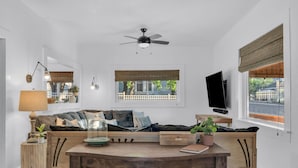 Una sala de estar moderna con una mesa de madera, sofá y ventilador de techo.