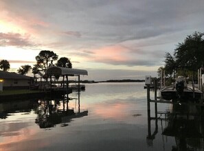 A waterfront dock with a covered structure, calm water, and distant trees. - IMPECCABLE CRYSTAL RIVER KING'S BAY WATERFRONT RETREAT - COMFORT & SERENITY (Crystal River)