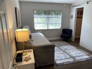 A cozy room with a gray sofa, a small side table with a lamp, a patterned rug, and a window with blinds. - IMPECCABLE CRYSTAL RIVER KING'S BAY WATERFRONT RETREAT - COMFORT & SERENITY (Crystal River)