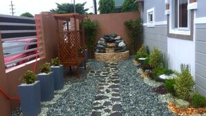 A garden pathway with stepping stones, a wooden pergola, and a rock garden.