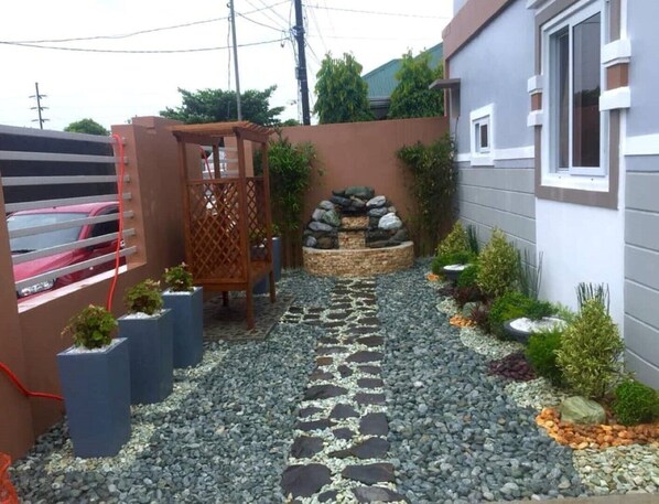 A garden pathway with stepping stones, a wooden pergola, and a rock garden. - E4 Apartment unit with covered parking (Pilar)