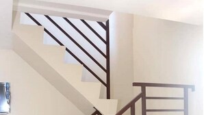 A modern staircase with wooden railings and a black mat at the bottom.