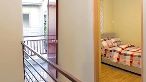 A bedroom with a bed, wooden floor, and a balcony with a railing.