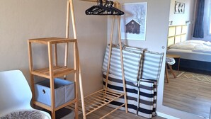 Una habitación con una estantería de madera, un sofá a rayas, una silla y una cama.