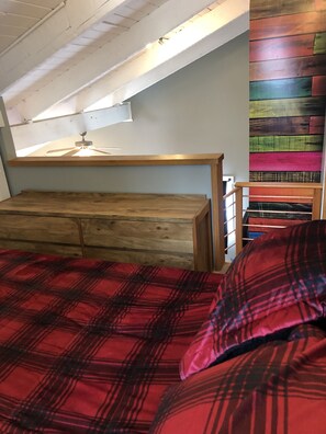 Une chambre avec un lit en bois, un ventilateur de plafond et un mur aux couleurs vives.