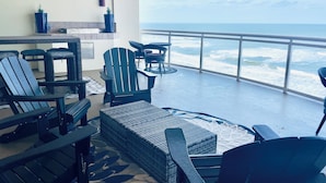 A balcony with wicker furniture, a view of the ocean, and a railing. - Fabulous direct ocean front with private balcony & steps to the beach (Daytona Beach)