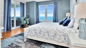 A bedroom with a bed, a nightstand, a lamp, and a view of the ocean. - Fabulous direct ocean front with private balcony & steps to the beach (Daytona Beach)