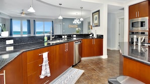 A modern kitchen with a large island, stainless steel appliances, and a view to the ocean. - Fabulous direct ocean front with private balcony & steps to the beach (Daytona Beach)