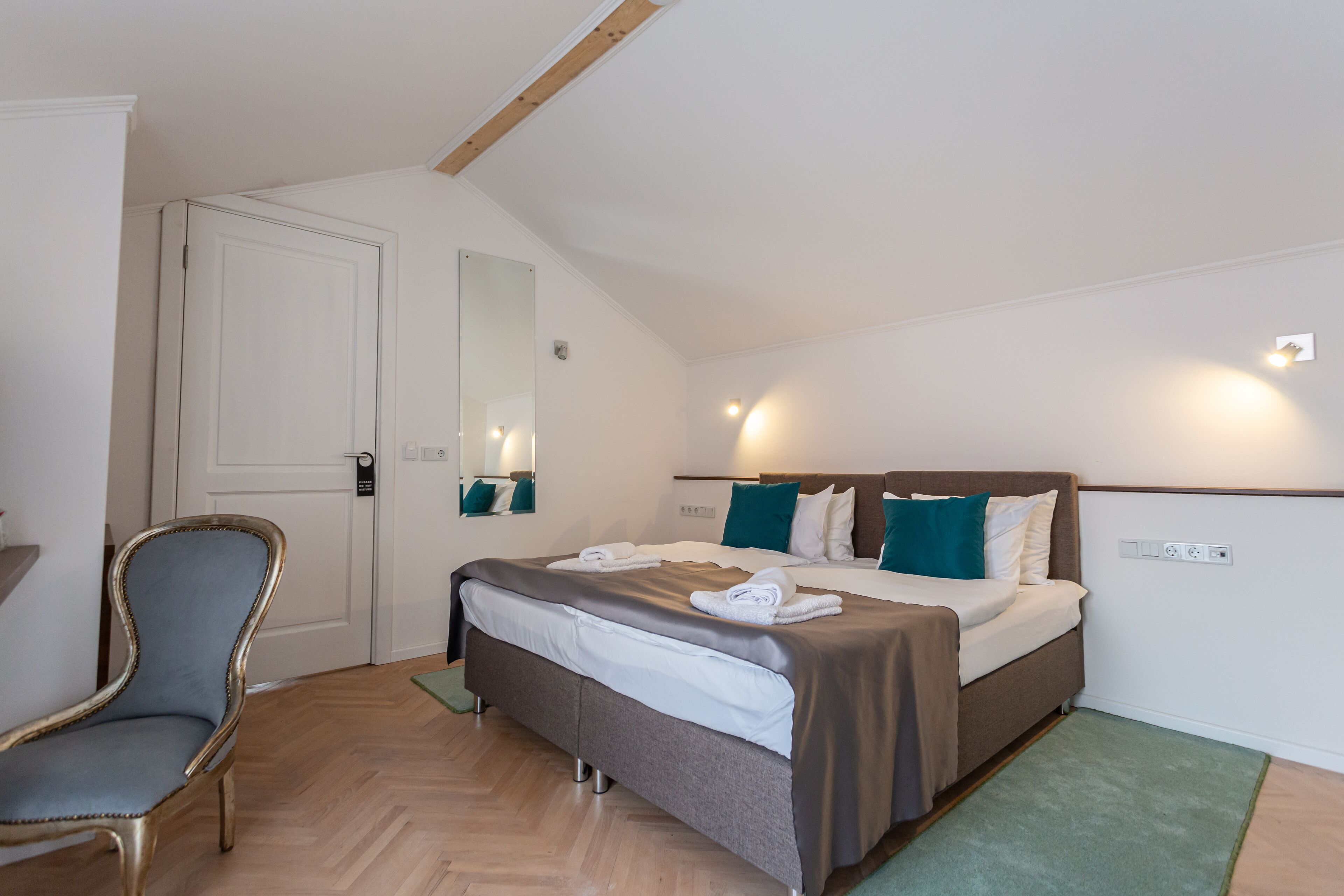 Un dormitorio con cama, una silla, un espejo y una puerta.