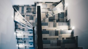 A modern staircase with geometric patterned tiles and recessed lighting. - Hotel Petrakija (Sarajevo)