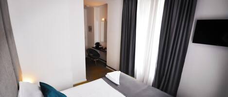 Ein Hotelzimmer mit zwei Betten, einem Schreibtisch und einem Fernseher.