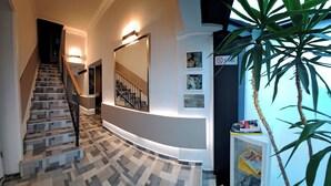 A modern interior with a staircase, a wall-mounted mirror, and a potted plant. - Hotel Petrakija (Sarajevo)
