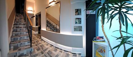 A modern interior with a staircase, a wall-mounted mirror, and a potted plant.