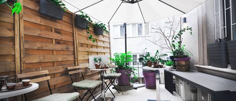 A cozy patio area with wooden benches, a table, and potted plants.