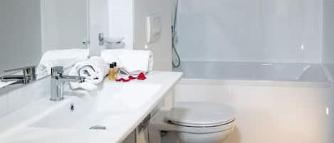 Un baño moderno con lavamanos, inodoro y ducha blancos.