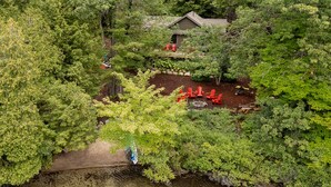 Una cabaña rodeada de un bosque denso, con un pequeño espacio de terraza y mobiliario exterior.