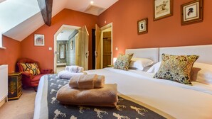 Une chambre à coucher avec un grand lit, deux oreillers, un fauteuil rouge et un miroir au mur.