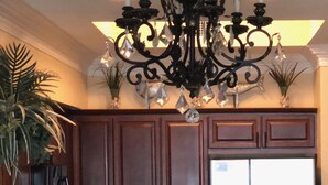 A kitchen with dark wooden cabinets, a stainless steel refrigerator, a chandelier, and a dining table with chairs. - Great rates!! PENTHOUSE BEACHFRONT!  Most Stunning View of Gulf Shores!!   (Gulf Shores)