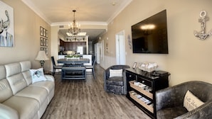 A living room with a sofa, a dark armchair, a coffee table, and a bookshelf. - Great rates!! PENTHOUSE BEACHFRONT!  Most Stunning View of Gulf Shores!!   (Gulf Shores)