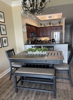 A dining area with a wooden table, benches, and a chandelier. - Great rates!! PENTHOUSE BEACHFRONT!  Most Stunning View of Gulf Shores!!   (Gulf Shores)