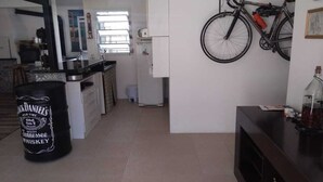Una cucina con frigorifero, forno a microonde e lavandino. Una bicicletta è appesa al muro.
