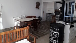 Un'area pranzo con una panca di legno, un tavolo e sedie. Si vede una botte nera con scritte.