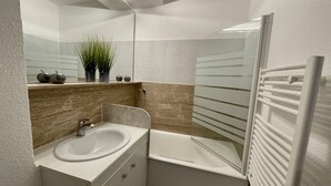 Ein Badezimmer mit Waschbecken, Spiegel und Badewanne.