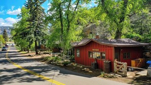 A red cabin with a sign reading "Reflection Cabin" surrounded by trees and a road.