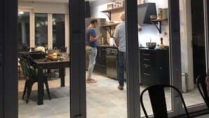 Moderni keittiö, jossa on liukuvat lasiovet, ruokailutila pöydän ja tuolien kera sekä näkyvissä oleva kattovalaisin.
