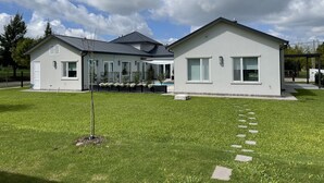 Moderni, kaksikerroksinen talo, jossa on katettu terassi, aidattu piha ja hyvin hoidettu nurmikko.